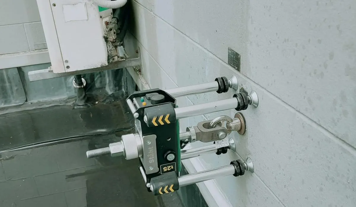 STAHT T25 digital pull tester proof load testing a wall-mounted eyebolt anchor point