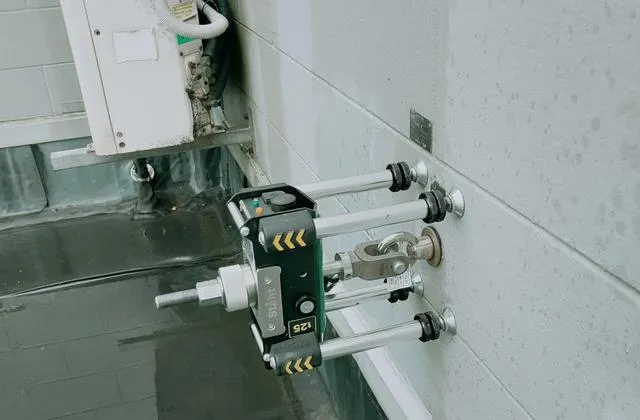 STAHT T25 digital pull tester proof load testing a wall-mounted eyebolt anchor point