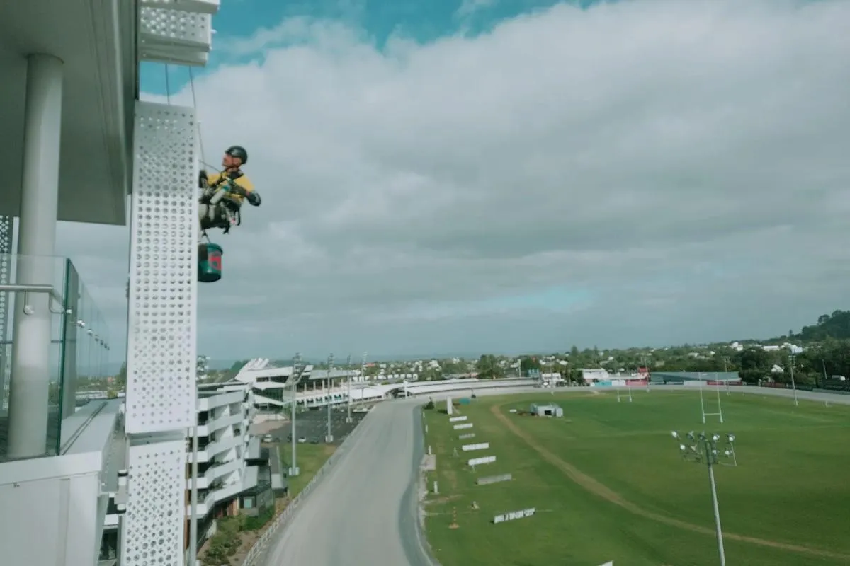 Alpine-Tech 360 rope access technician servicing shutter screens on a commercial building in Auckland