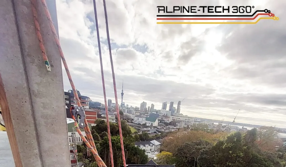 Alpine-Tech 360 rope access technician sealing a building facade joint high above the Auckland skyline