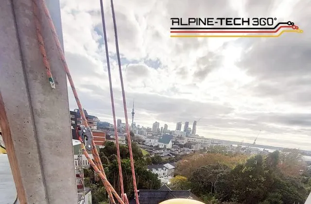 Alpine-Tech 360 rope access technician sealing a building facade joint high above the Auckland skyline